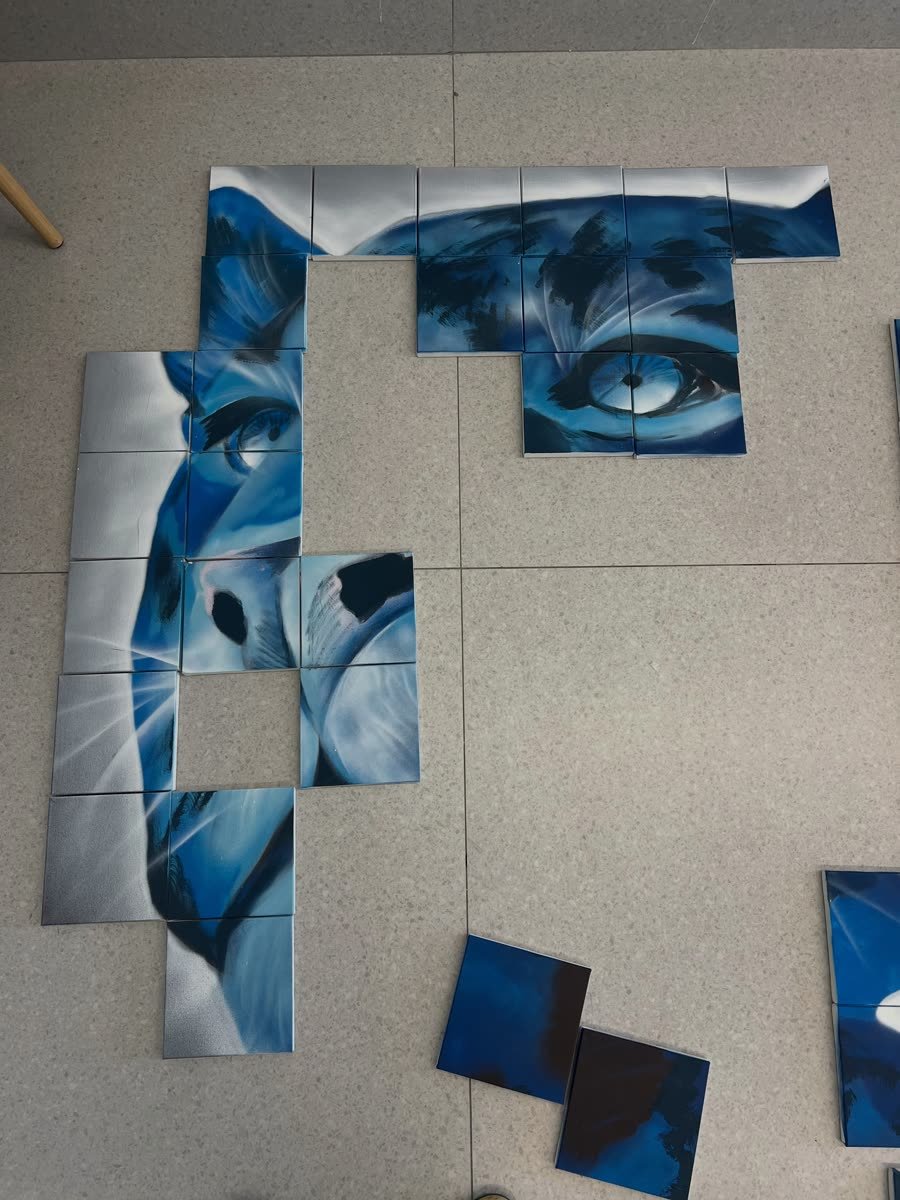 Peças pintadas de um mural em azul espalhadas no chão como quebra-cabeça