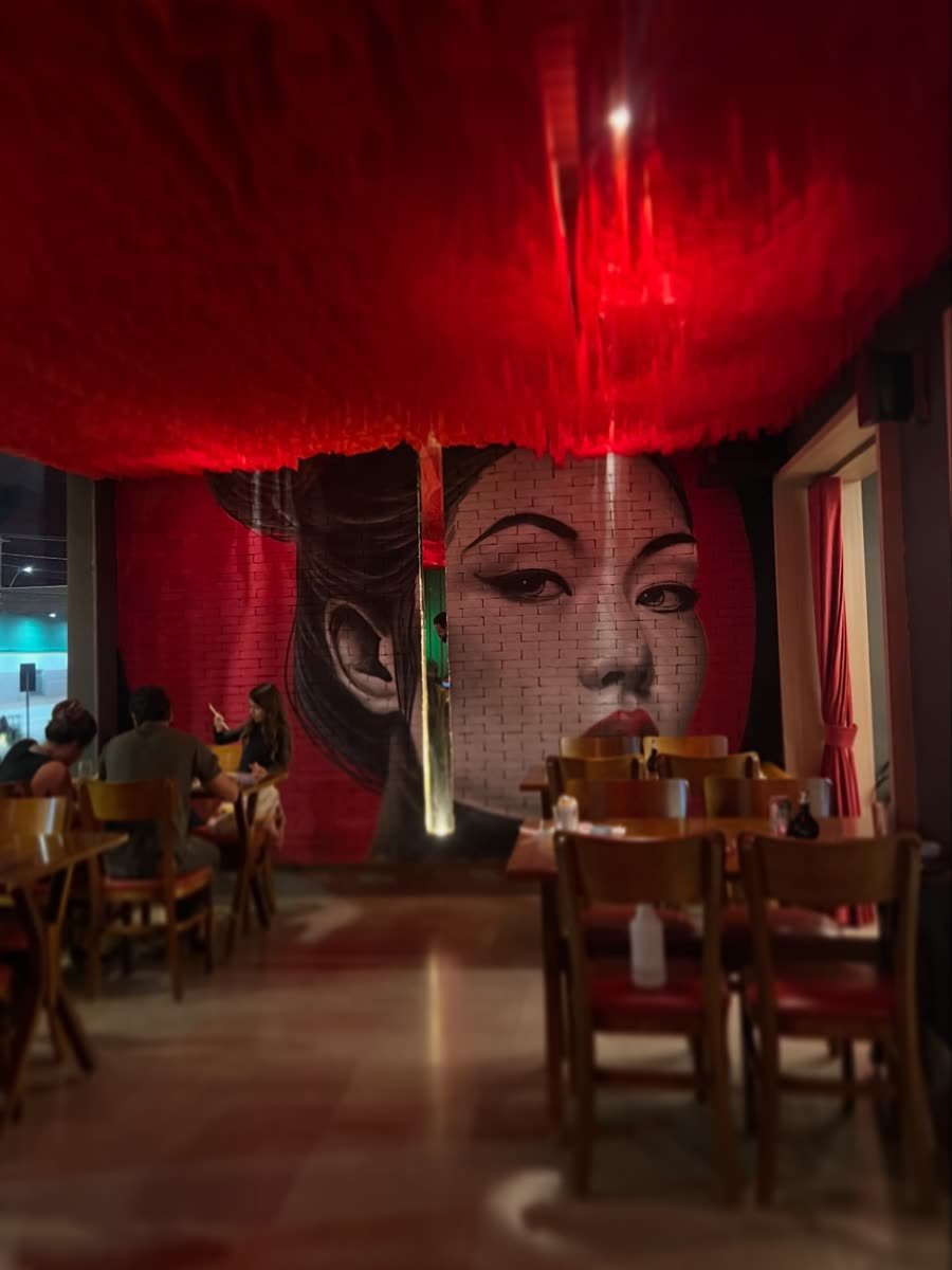 Restaurante com retrato de mulher pintado na parede sob luz vermelha